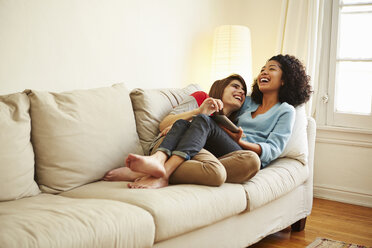 Junges weibliches Paar auf dem Sofa liegend mit Blick auf ein digitales Tablet - ISF14646