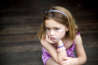 Mürrisches junges Mädchen sitzt auf der Veranda mit den Händen am Kinn - ISF14651