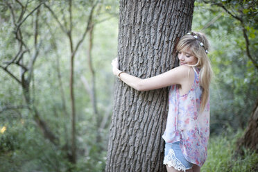 Teenage girl hugging tree in woodland - ISF14717