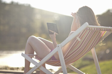 Young woman on deckchair using digital tablet - ISF14734