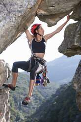 Young female rock climber balancing on rock face - ISF14749