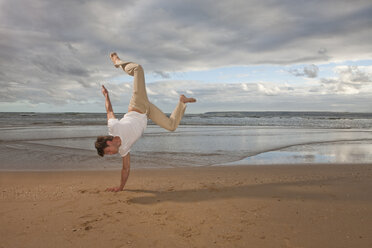 Junger Mann macht Handstand am Strand - ISF14770