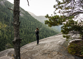 Junge Frau schaut auf ihr Smartphone, Squamish, British Columbia, Kanada - ISF15016