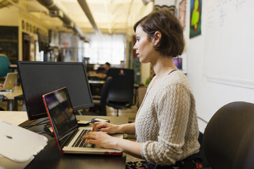 Junge Designerin mit Laptop im Studio - ISF15049