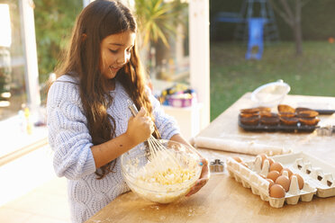 Girl beating mixture in bowl in kitchen - CUF38017