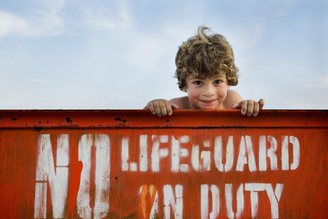 Porträt eines Jungen und Rettungsschwimmerschild, Long Beach, New York State, USA, lizenzfreies Stockfoto