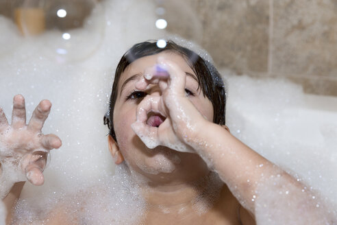 Young boy blowing bubbles in bubble bath - ISF15219