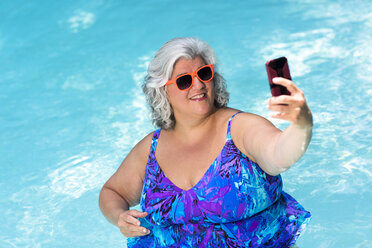 Reife Frau nimmt Selfie auf Smartphone am Pool - ISF15318