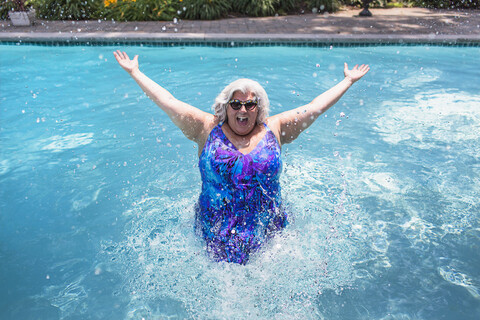Portrait of mature woman splashing about in swimming pool stock photo