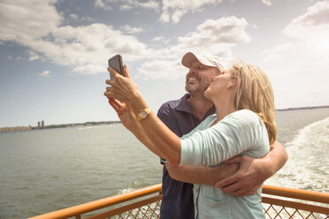Mature couple photographing themselves on passenger ferry deck - ISF15331