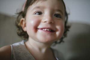 Happy baby girl with big smile sitting on the couch at home - GEMF02101