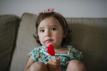 Niedliches kleines Mädchen isst einen herzförmigen Lutscher zu Hause - GEMF02103