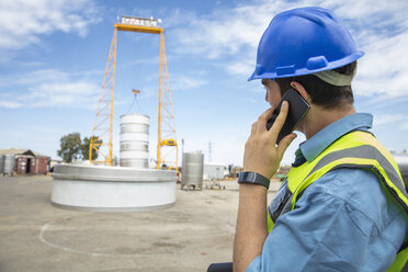 Man in workwear on construction site talking on cell phone - ZEF15749