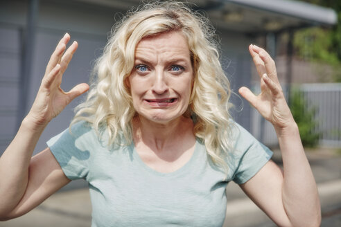 Portrait of grimacing woman outdoors - RHF02065