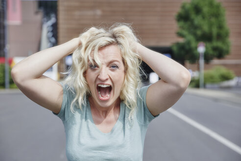 Portrait of screaming woman pulling her hair - RHF02067