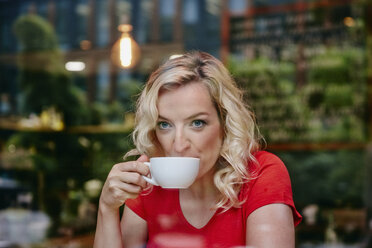 Porträt einer blonden Frau beim Kaffeetrinken in einem Café - RHF02069