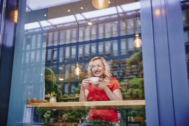 Smiling blond woman drinking coffee in a cafe - RHF02070