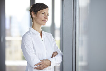 Businesswoman in office looking out of window - RBF06356