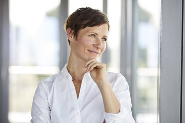 Porträt einer lächelnden Geschäftsfrau im Büro mit Blick zur Seite - RBF06368