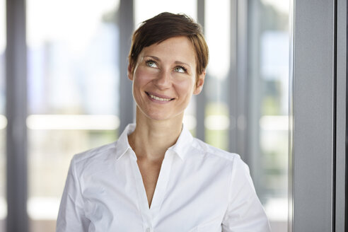 Portrait of smiling businesswoman in office looking up - RBF06370