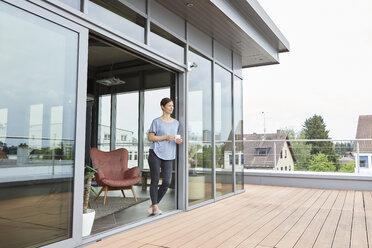 Frau zu Hause mit einer Tasse Kaffee auf der Dachterrasse - RBF06388