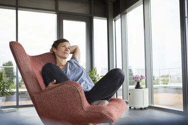 Woman sitting in armchair at home relaxing - RBF06396