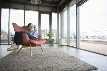 Woman sitting in armchair at home relaxing - RBF06400