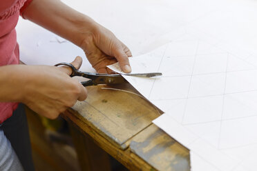 Close-up of woman cutting paper from draft in glazier's workshop - BFRF01863