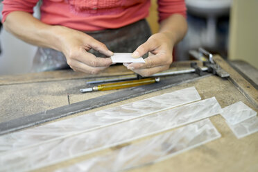 Nahaufnahme einer Frau bei der Arbeit an einer Glasscheibe in einer Glaserei - BFRF01866