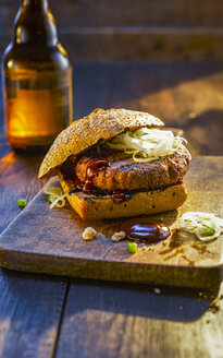 Burger auf einem Holzbrett neben einer Bierflasche - KSWF01926