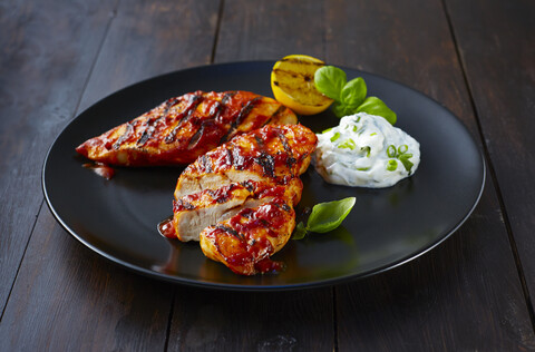 Gegrilltes Hähnchenbrustfilet mit saurer Sahne auf Teller, lizenzfreies Stockfoto