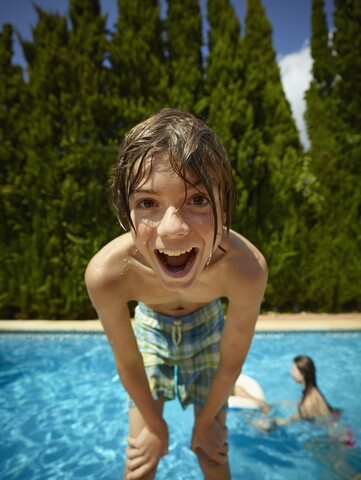 Porträt eines Jungen, der sich vor einem Schwimmbad nach vorne lehnt, Mallorca, Spanien, lizenzfreies Stockfoto