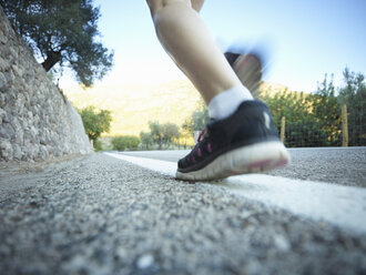Surface level view of teenage girls legs running on road, Majorca, Spain - CUF38108