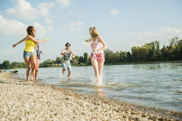 Friends playing with water pistols in lake - CUF38124