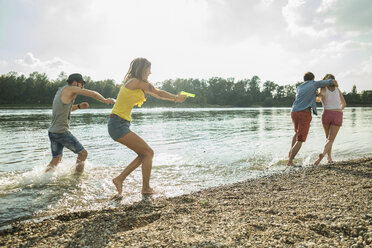 Freunde spielen mit Wasserpistolen im See - CUF38125