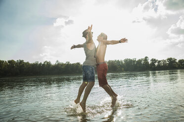 Young men chest bumping in lake - CUF38131