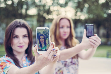 Zwei junge Freundinnen machen unisono ein Selfie mit ihren Smartphones - CUF38161
