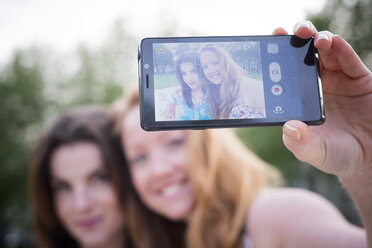 Close up of two young female friends taking selfie on smartphone in park - CUF38163