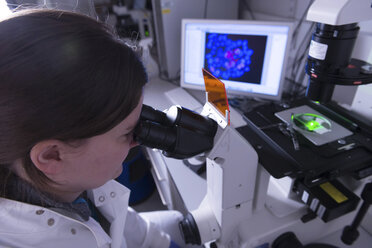 Cancer research laboratory, female scientist studying electronic microscope - CUF38191