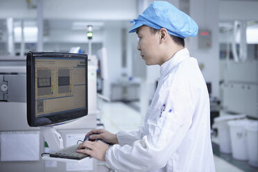 Arbeiter am Computer in einer Fabrik, die auf die Herstellung funktioneller Schaltkreise auf flexiblen Oberflächen spezialisiert ist - CUF38213