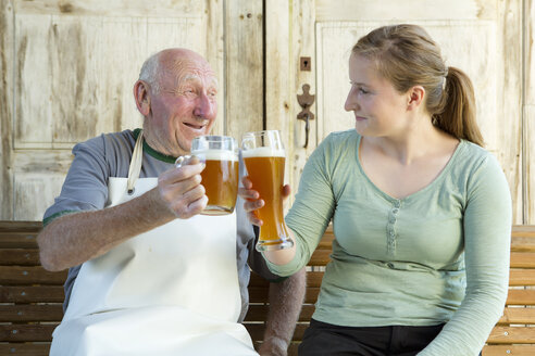 Älterer Mann und junge Frau stoßen mit Bier an - CUF38226