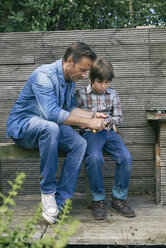 Vater zeigt seinem Sohn, wie man ein Taschenmesser im Kleingarten benutzt - CUF38266