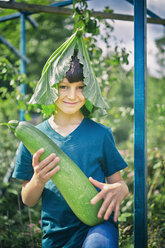 Porträt eines Jungen mit Blätterhut und Kürbis im Schrebergarten - CUF38279