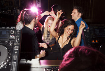 Group of friends dancing in front of DJ in nightclub - CUF38404