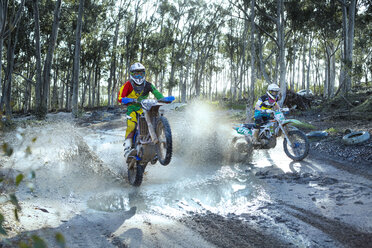 Zwei junge männliche Motocross-Fahrer fahren auf einer staubigen Strecke - CUF38533