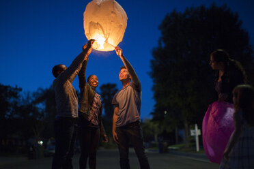 Friends holding up sky lantern to celebrate - ISF15353