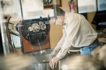 Älterer Mann mit Kaffeeröstmaschine in einem Cafe - ISF15373