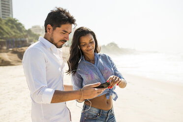 Paar wählt Musik vom Smartphone aus, Strand von Arpoador, Rio De Janeiro, Brasilien - ISF15422