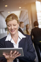 Mature woman using touchscreen on digital tablet in office corridor - ISF15436