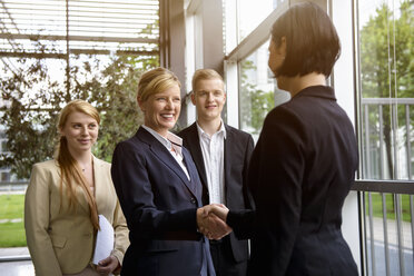 Business team greeting young female colleague - ISF15439